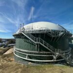 close up of a green anaerobic digestion tank with white dome with blue skies on green grass