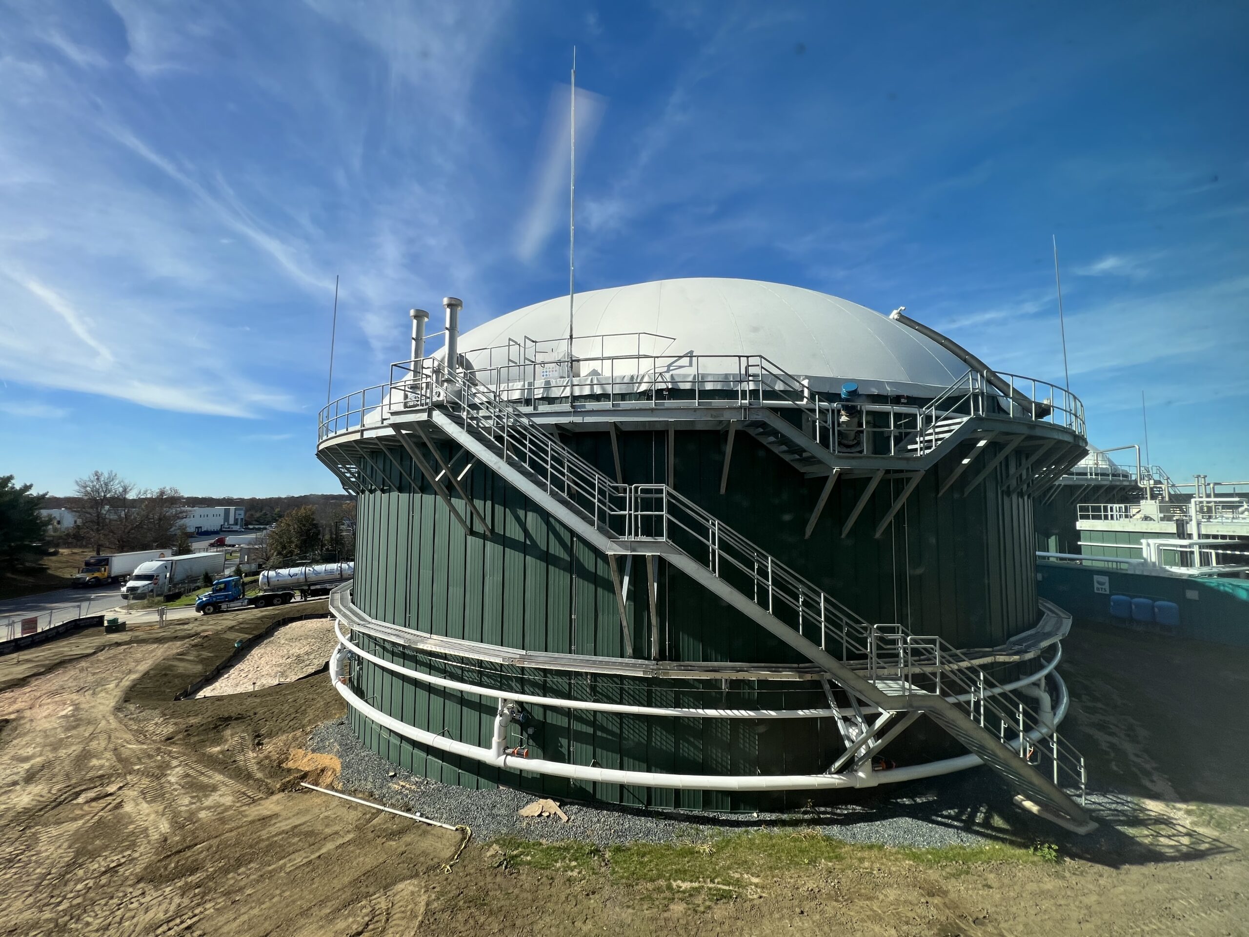 close up of a green anaerobic digestion tank with white dome with blue skies on green grass